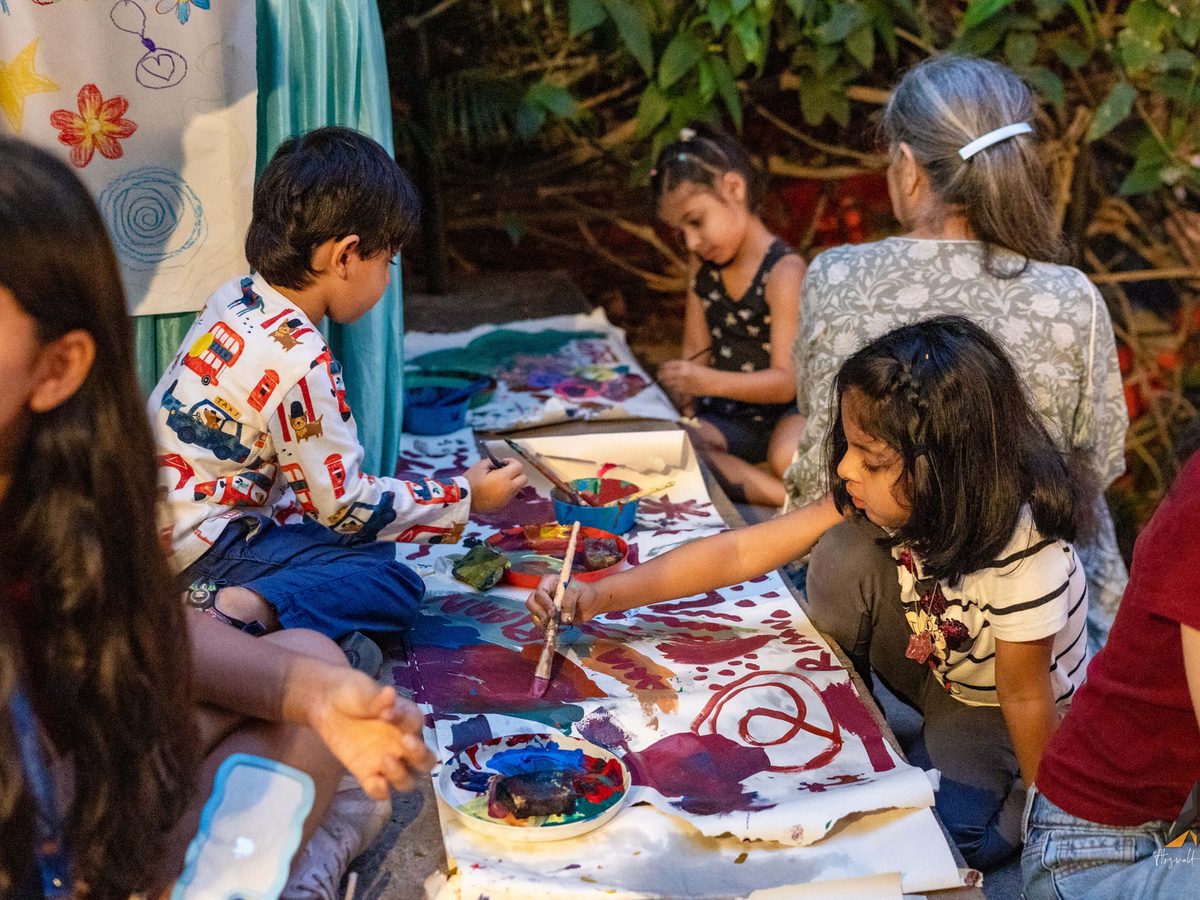 Children painting on a long canvas laid on the ground