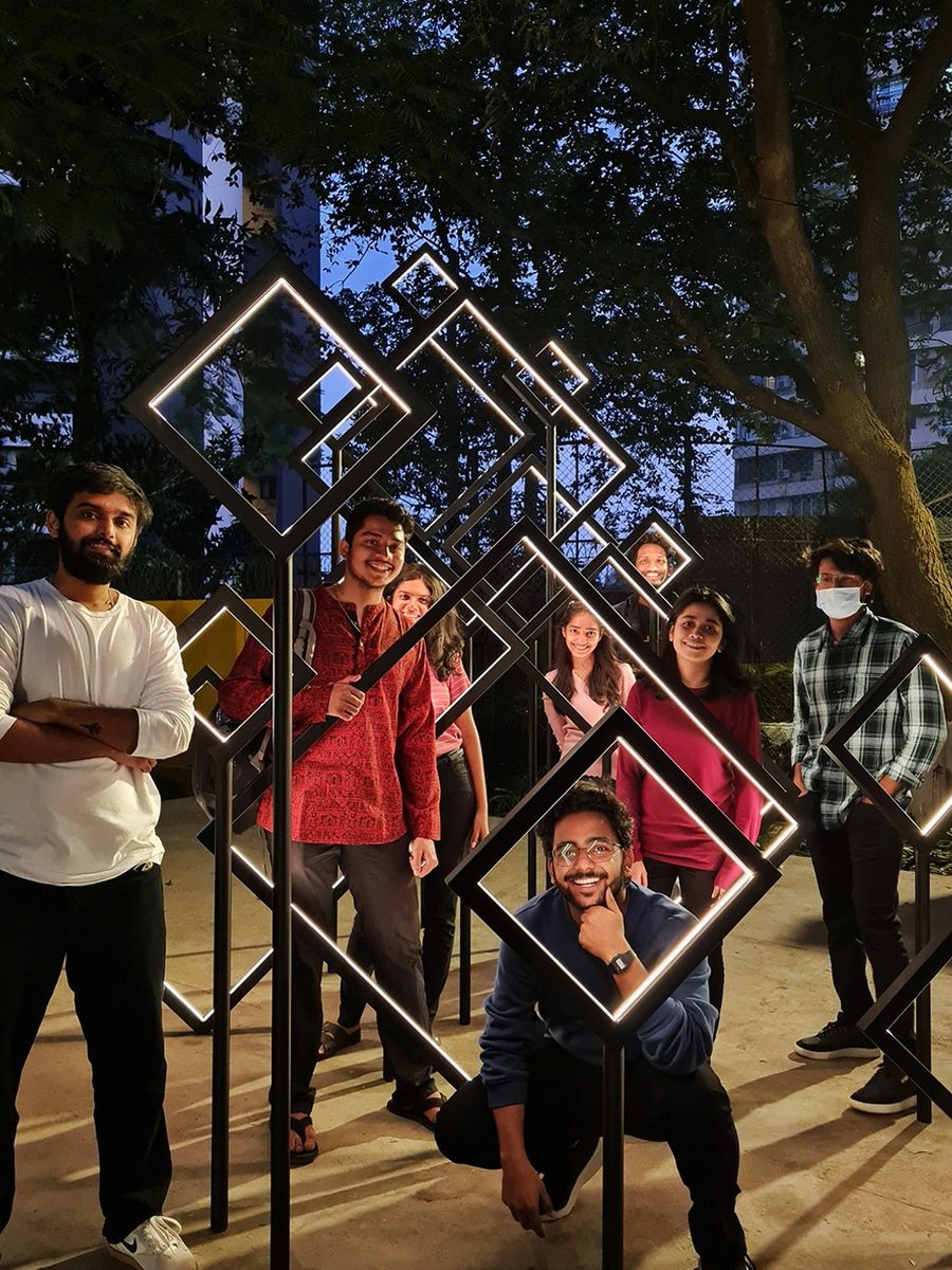 Friends posing inside the Family Tree, a frame of lit diamond shapes