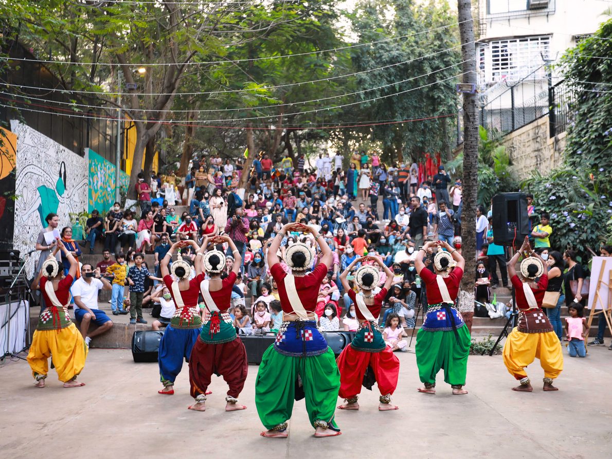 Folk dancers in red and green performing to a packed crowd on The Steps