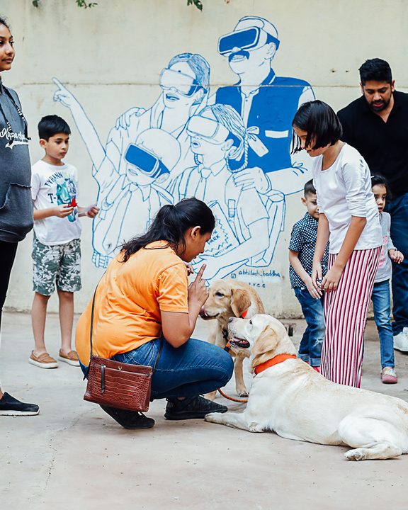 Visitors and a dog in front of a blue line-drawn mural