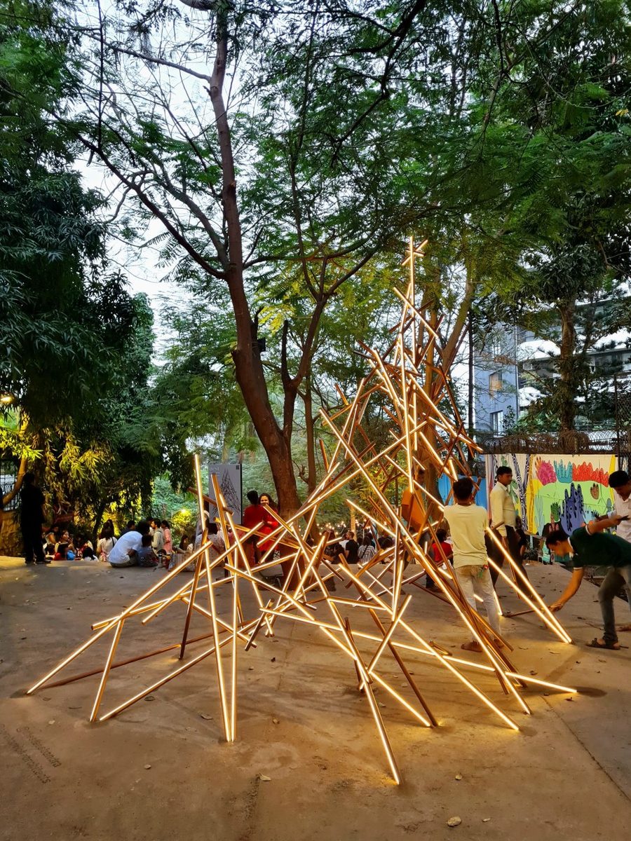 The Nest Tree: a woven cone of glowing rods among the trees