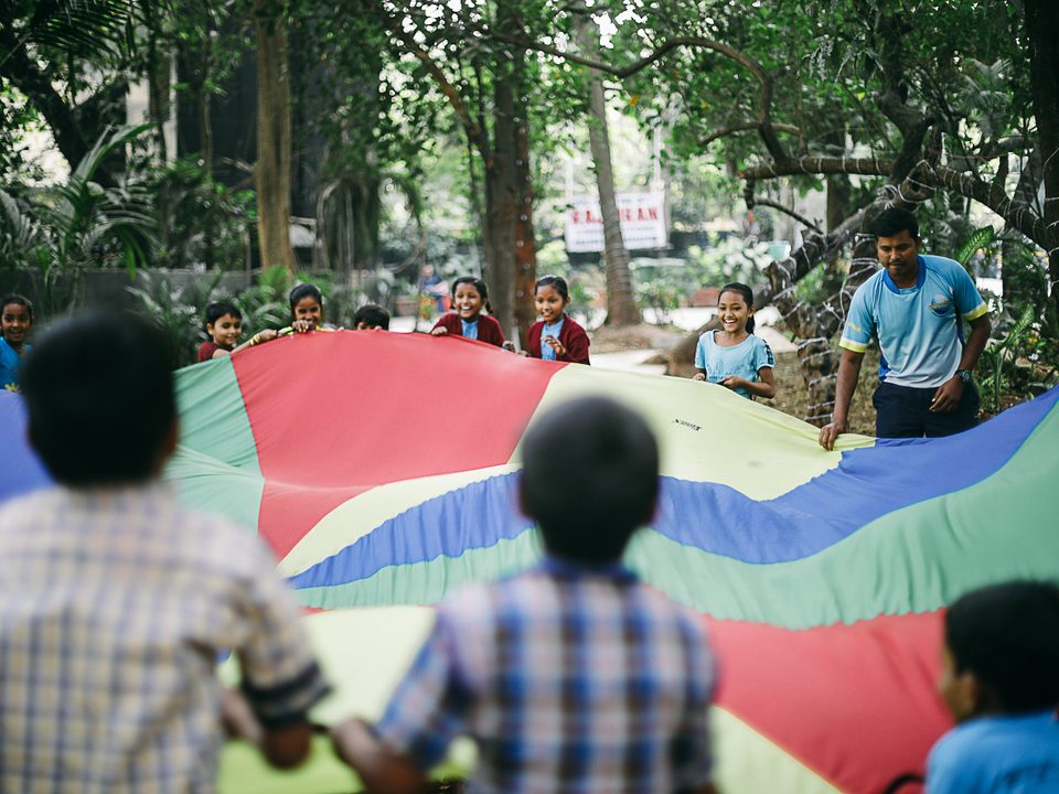 Children playing with a giant rainbow parachute