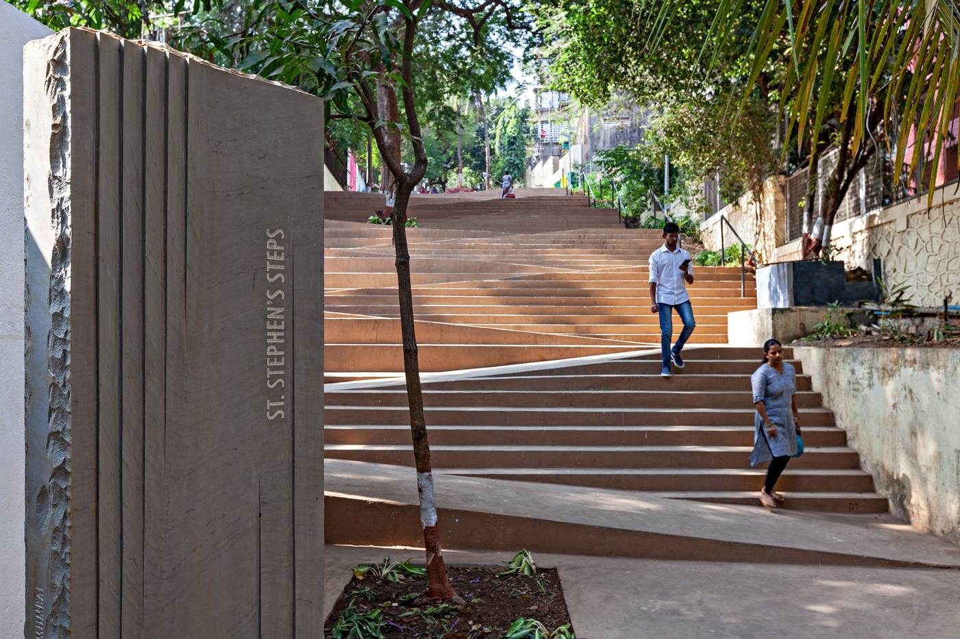 A carved stone marker reading St. Stephen's Steps, with people walking down the steps behind it